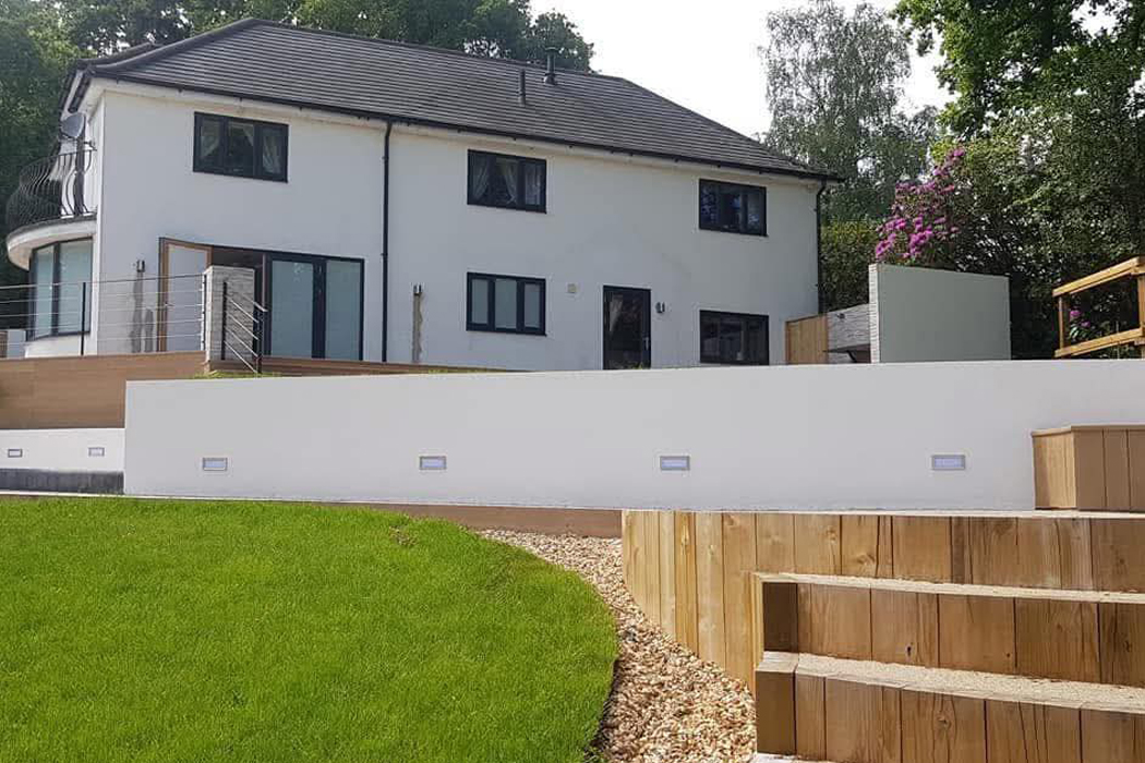 Modern property with high-quality machine-applied spray rendering on exterior walls and a retaining wall, demonstrating a smooth, professional finish